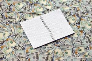 Office workplace table with blank notebook or notepad and many hundred dollar bills photo