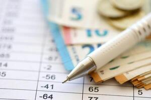 Business concept with many euro money bills and pen on schedules with calculations photo