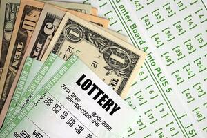 Green lottery tickets and US money bills on blank with numbers for playing lottery photo