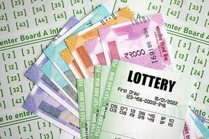 Green lottery tickets and indian rupees money bills on blank with numbers for playing lottery photo