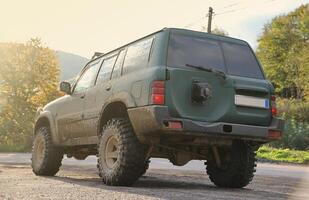 Automobile in a countryside landscape with a mud road. Off-road 4x4 suv automobile with ditry body after drive in muddy road photo