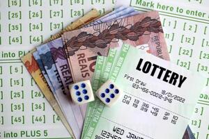 Green lottery tickets and brazilian reals money bills on blank with numbers for playing lottery photo