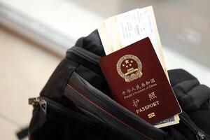 Red passport of People Republic of China with airline tickets on backpack photo
