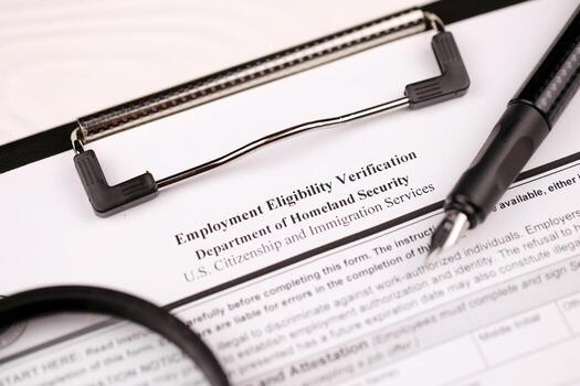 I-9 Employment Eligibility Verification blank form on A4 tablet lies on office table with pen and magnifying glass photo