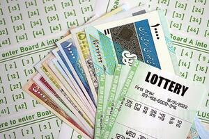 Green lottery tickets and iranian money bills on blank with numbers for playing lottery photo