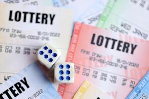 Many lottery tickets and dice on blank bills with numbers for playing lottery photo