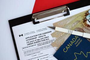 Application for Canadian citizenship for adults on table with pen, passport and dollar bills photo