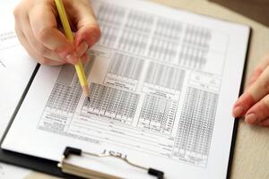 Female student hands testing in exercise and taking fill in exam paper sheet with pencil at school test photo