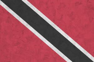 Trinidad and Tobago flag depicted in bright paint colors on old relief plastering wall. Textured banner on rough background photo