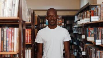 Black Man In Library Turns And Looks At Camera Smiles, Standing Between The photo
