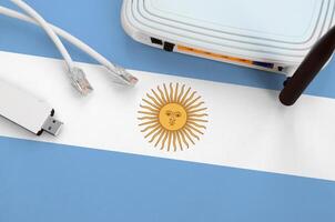 Argentina flag depicted on table with internet rj45 cable, wireless usb wifi adapter and router. Internet connection concept photo
