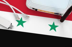 Syria flag depicted on table with internet rj45 cable, wireless usb wifi adapter and router. Internet connection concept photo