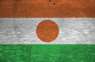 Niger flag depicted in paint colors on old brick wall. Textured banner on big brick wall masonry background photo