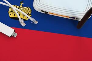 Liechtenstein flag depicted on table with internet rj45 cable, wireless usb wifi adapter and router. Internet connection concept photo
