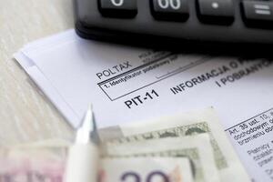 Information on revenues from other sources and collected income tax advances, PIT-11 form on accountant table with pen and polish zloty money bills photo