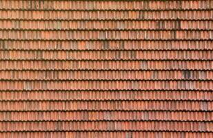 Close up of red terracotta roof shingles with some mildew. Background texture of roofing material photo