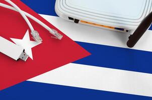 Cuba flag depicted on table with internet rj45 cable, wireless usb wifi adapter and router. Internet connection concept photo