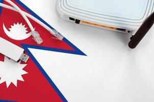 Nepal flag depicted on table with internet rj45 cable, wireless usb wifi adapter and router. Internet connection concept photo
