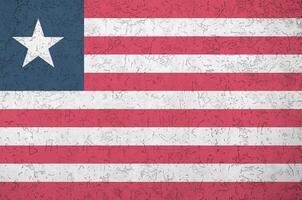 Liberia flag depicted in bright paint colors on old relief plastering wall. Textured banner on rough background photo