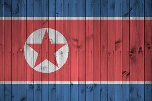 North Korea flag depicted in bright paint colors on old wooden wall. Textured banner on rough background photo