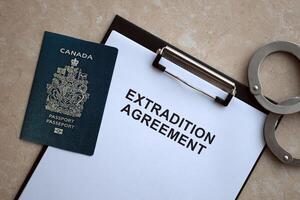 Passport of Canada and Extradition Agreement with handcuffs on table photo