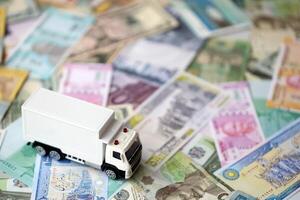 Delivery truck on many banknotes of different currency. Background of trucking or moving concept photo