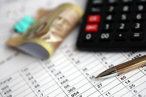Many calculation results in schedules lies on table with canadian money bills, calculator and pen photo