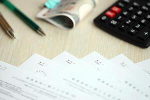 Japanese tax forms lies on table with calculator, pen and japanese yen money bills roll photo