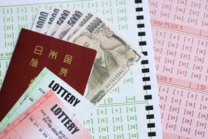 Lottery tickets lies with japanese yen bills on gambling sheets with numbers for marking to play lottery photo