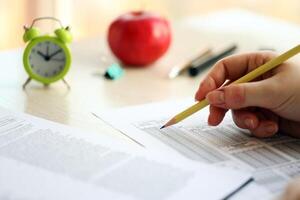 Female student hands testing in exercise and taking fill in exam paper sheet with pencil at school test photo