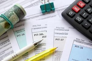 Declaration of the amount of earned income or incurred loss, PIT-36, PIT-36L, PIT-37 and PIT-38 tax forms on accountant table with pen and polish zloty money bills photo