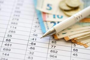 Business concept with many euro money bills and pen on schedules with calculations photo