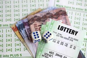 Green lottery tickets and brazilian reals money bills on blank with numbers for playing lottery photo