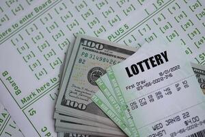 Green lottery tickets and US money bills on blank with numbers for playing lottery photo
