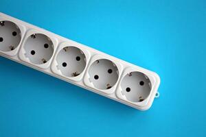 White electrical multi plug extender with european socket on bright blue background photo