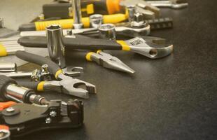 Handyman tool kit on black wooden table. Many wrenches and screwdrivers, pilers and other tools for any types of repair or construction works. Repairman tools photo