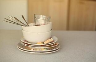 Stack of dirty dishes with food leftovers on the table after meal. Banquet ending concept. Unwashed dishes photo