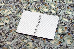 Office workplace table with blank notebook or notepad and many hundred dollar bills photo