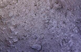 Close up of muddy puddle with small stones on wet surface. Background texture with top view photo