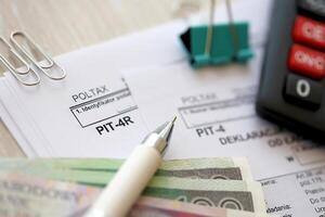 Annual declaration of income tax advances, PIT-4R form on accountant table with pen and polish zloty money bills photo
