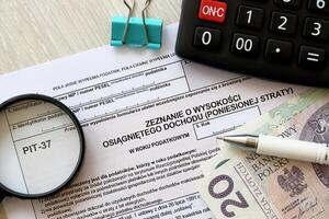 Declaration of the amount of earned income or incurred loss PIT-37 tax forms on accountant table with pen and polish zloty money bills photo