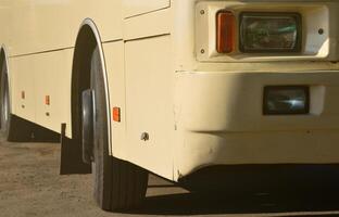Photo of the hull of a large and long yellow bus. Close-up front view of a passenger vehicle for transportation and tourism