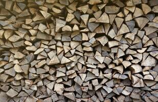 Firewood stacked near the wooden wall of old hut. Many chopped logs of firewood photo