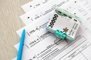 Annual Individual Income Tax Return forms with pen and indonesian rupiah bills photo