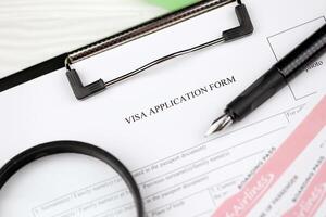 Typical Visa application form on A4 tablet lies on office table with pen and magnifying glass photo