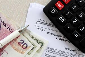 Information on revenues from other sources and collected income tax advances, PIT-11 form on accountant table with pen and polish zloty money bills photo