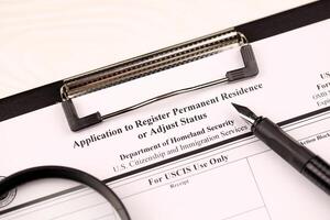 I-485 Application to register permanent residence or adjust status blank form on A4 tablet lies on office table with pen and magnifying glass photo