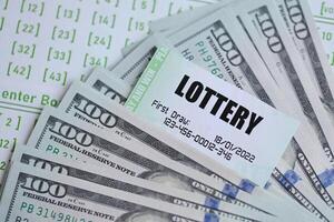 Green lottery tickets and US money bills on blank with numbers for playing lottery photo