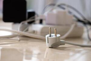 Overloaded power boards. Power strips with different electrical plugs on white floor photo