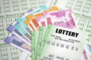Green lottery tickets and indian rupees money bills on blank with numbers for playing lottery photo